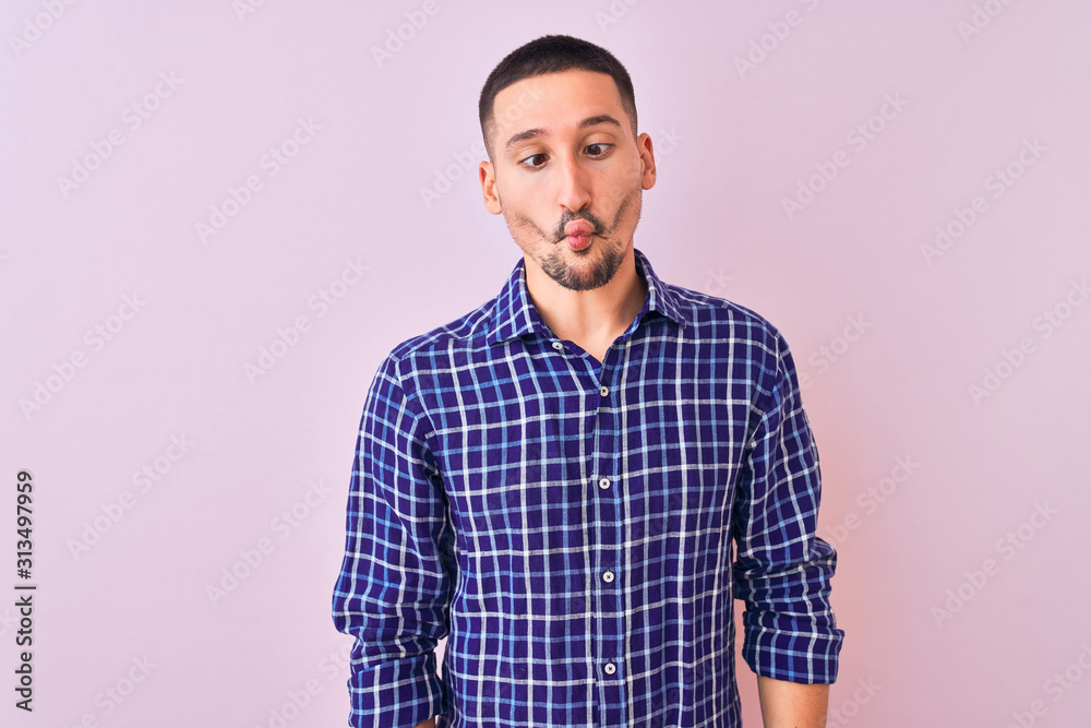 Young handsome man standing over isolated background making fish face with lips, crazy and comical gesture. Funny expression. Young handsome man standing over isolated background making fish face with lips, crazy and comical gesture. Funny expression.