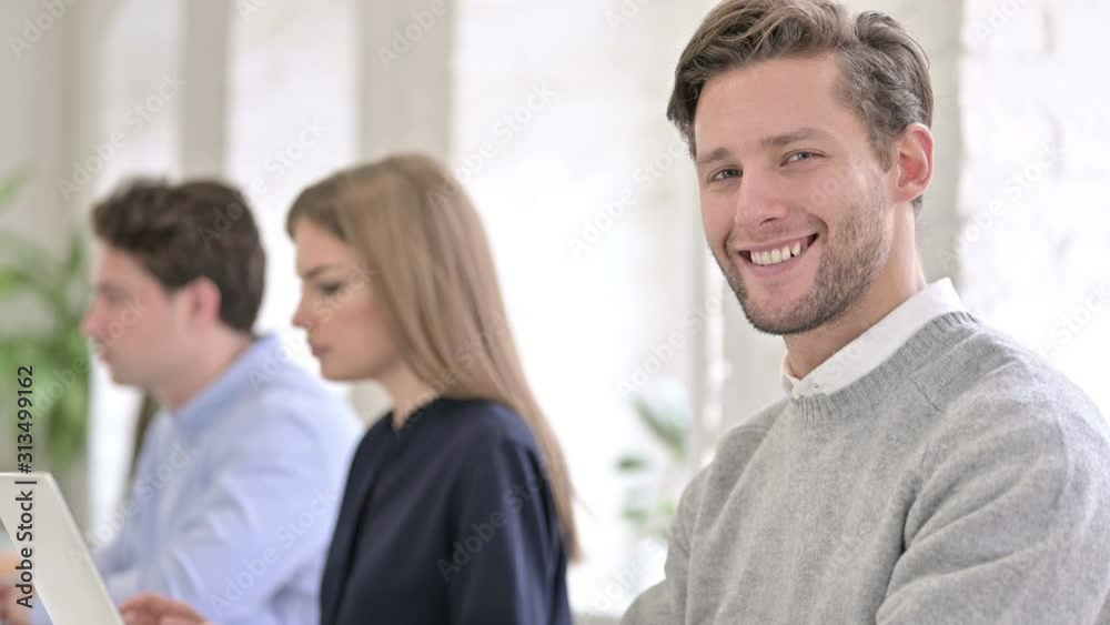 Portrait of Attractive Creative Man and Smiling at the Camera in Office Portrait of Attractive Creative Man and Smiling at the Camera in Office