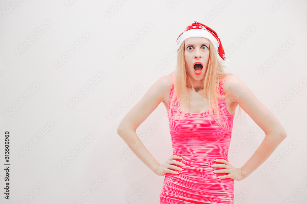blonde in a red Christmas hat and pink dress shows different emotions on her face blonde in a red Christmas hat and pink dress shows different emotions on her face