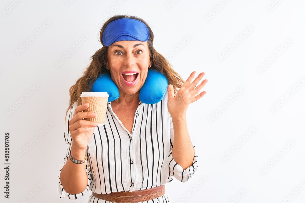 Tourist woman wearing neckpillow sleep mask drinking coffee over isolated white background very happy and excited, winner expression celebrating victory screaming with big smile and raised hands Tourist woman wearing neckpillow sleep mask drinking coffee over isolated white background very happy and excited, winner expression celebrating victory screaming with big smile and raised hands