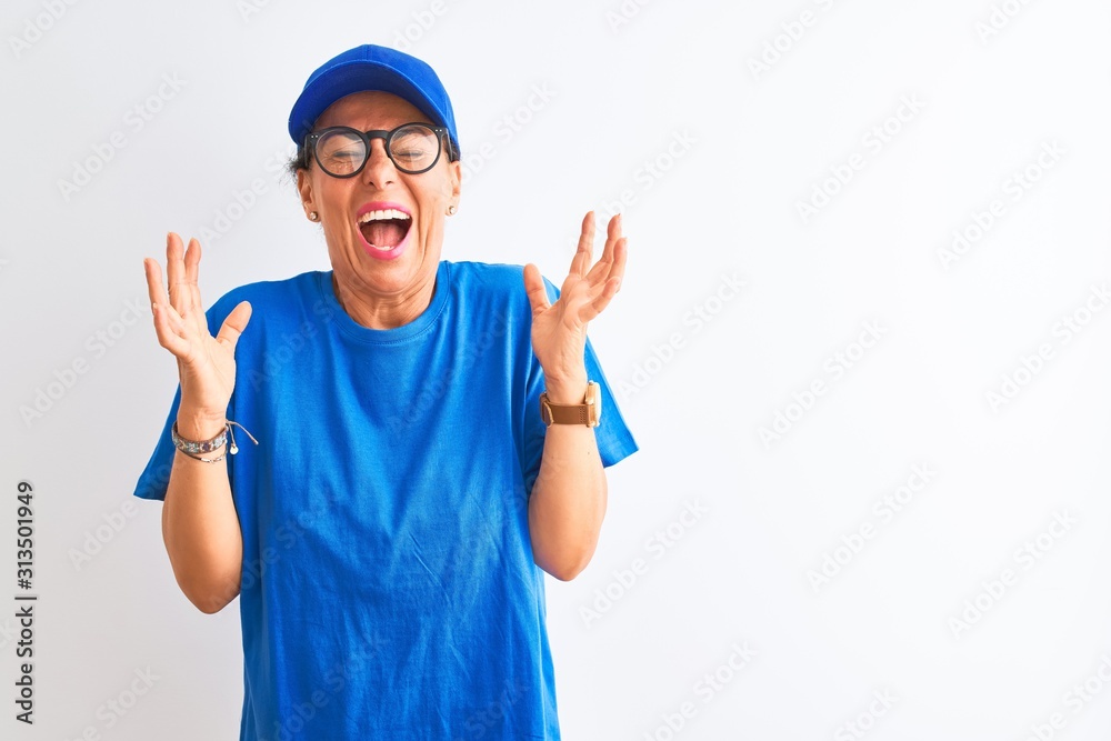 Senior deliverywoman wearing cap and glasses standing over isolated white background celebrating mad and crazy for success with arms raised and closed eyes screaming excited. Winner concept Senior deliverywoman wearing cap and glasses standing over isolated white background celebrating mad and crazy for success with arms raised and closed eyes screaming excited. Winner concept