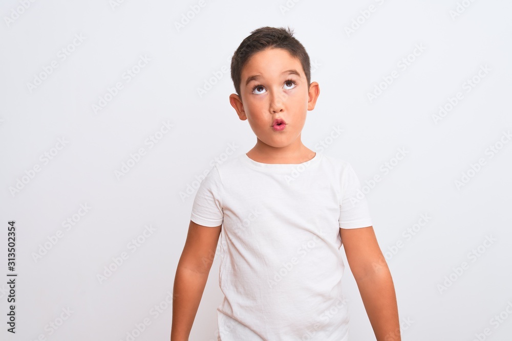 Beautiful kid boy wearing casual t-shirt standing over isolated white background making fish face with lips, crazy and comical gesture. Funny expression. Beautiful kid boy wearing casual t-shirt standing over isolated white background making fish face with lips, crazy and comical gesture. Funny expression.