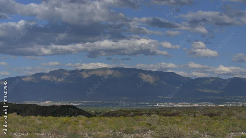 Stunning time-lapse overlooking the distant city of Albuquerque, New Mexico with blue skies and clouds moving over city with desert mountains in background. Stunning time-lapse overlooking the distant city of Albuquerque, New Mexico with blue skies and clouds moving over city with desert mountains in background.