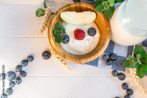 Fototapeta Naklejka Na Ścianę i Meble -  yogurt with whole fresh blueberries raspberries on wooden table. Healthy eating