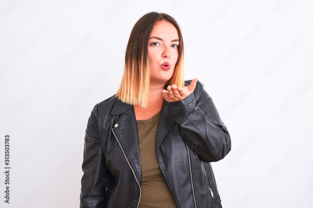 Young beautiful woman wearing t-shirt and jacket standing over isolated white background looking at the camera blowing a kiss with hand on air being lovely and sexy. Love expression. Young beautiful woman wearing t-shirt and jacket standing over isolated white background looking at the camera blowing a kiss with hand on air being lovely and sexy. Love expression.