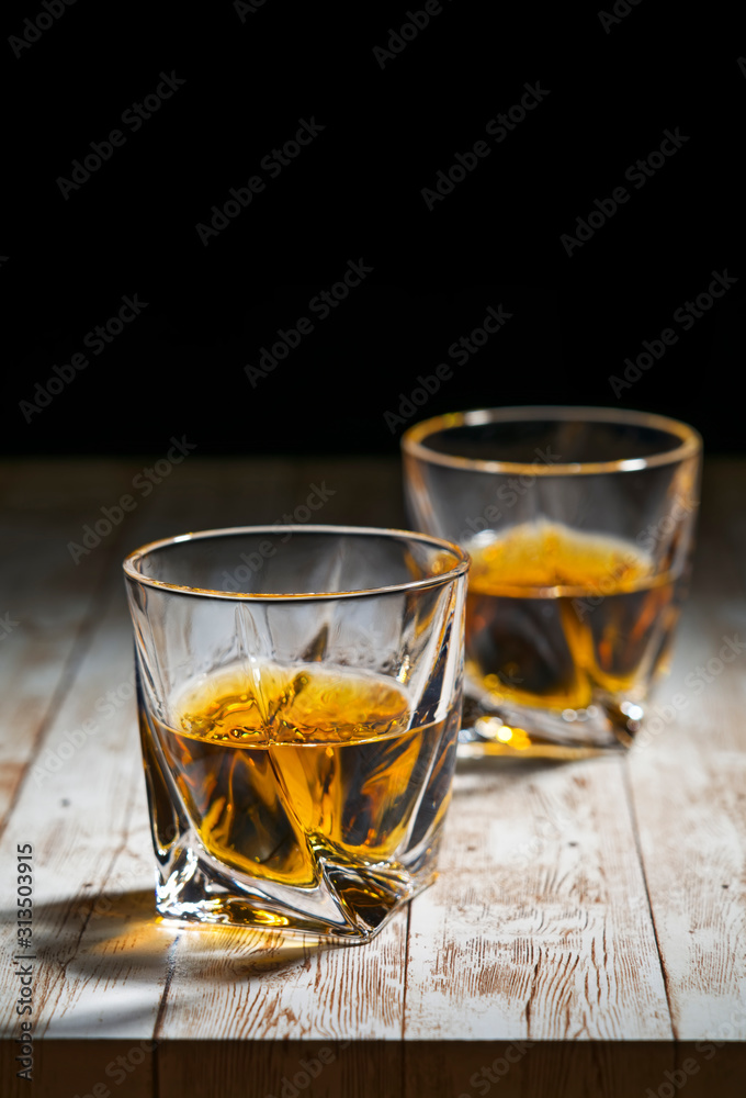 View of two filled whiskey glasses on a wooden bar top View of two filled whiskey glasses on a wooden bar top