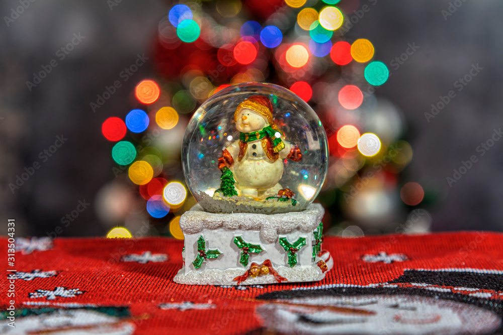 Snow globe with snowman and Christmas tree in the background.