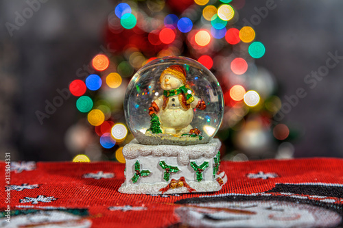 Obraz na płótnie Snow globe with snowman and Christmas tree in the background. w salonie