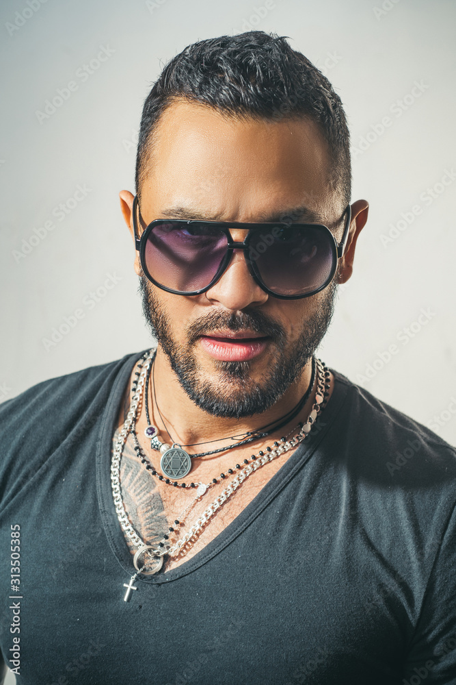 Obraz premium Charming man with sunglasses. Man face. Portrait of a handsome masculine man. Portrait of satisfied businessman against grey wall. Sunglasses. City fashion style.