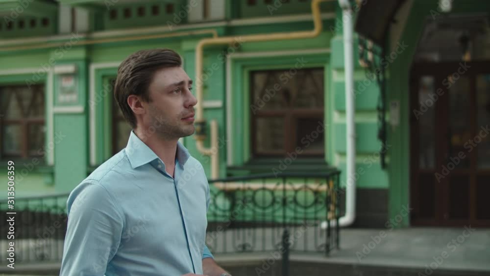 Young man talking by wireless headphones outside. Man using bluetooth earphone Young man talking by wireless headphones outside. Man using bluetooth earphone