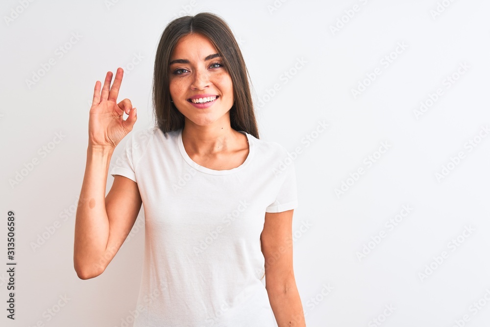 Young beautiful woman wearing casual t-shirt standing over isolated white background smiling positive doing ok sign with hand and fingers. Successful expression. Young beautiful woman wearing casual t-shirt standing over isolated white background smiling positive doing ok sign with hand and fingers. Successful expression.