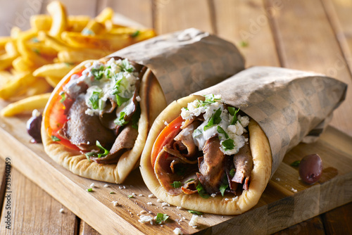 two greek gyros with shaved lamb and french fries photo