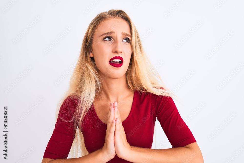 Young beautiful woman wearing red t-shirt standing over isolated white background begging and praying with hands together with hope expression on face very emotional and worried Young beautiful woman wearing red t-shirt standing over isolated white background begging and praying with hands together with hope expression on face very emotional and worried