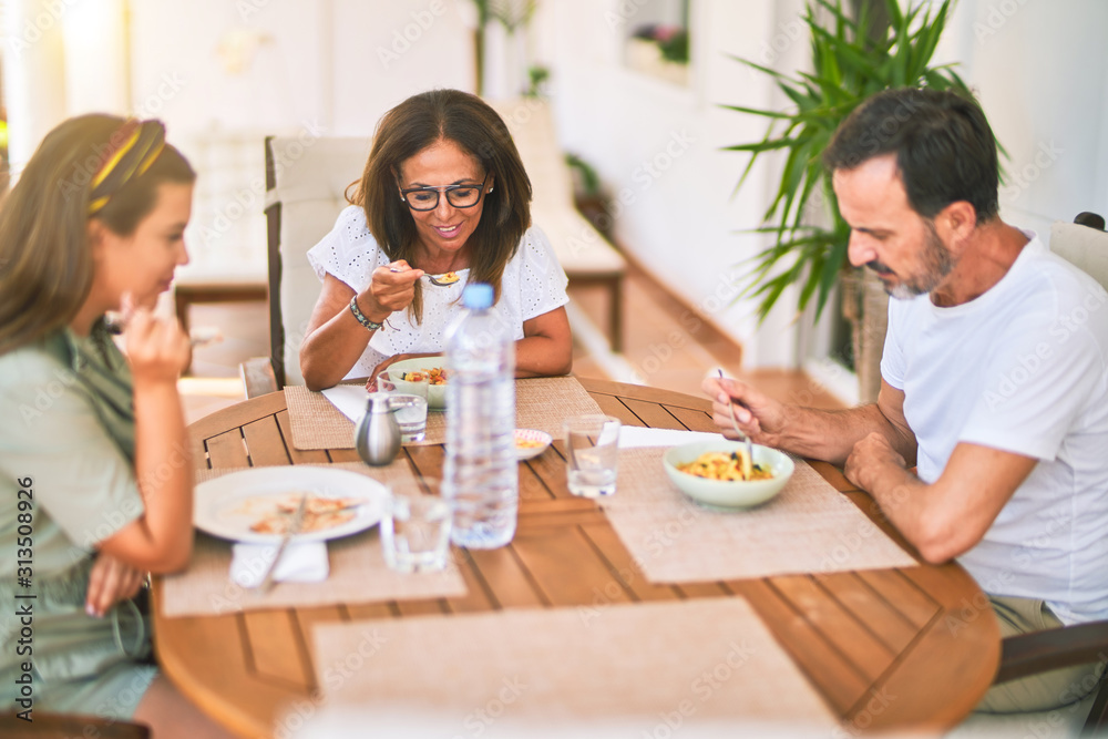 Beautiful family sitting on terrace eating foods speaking and smiling Beautiful family sitting on terrace eating foods speaking and smiling