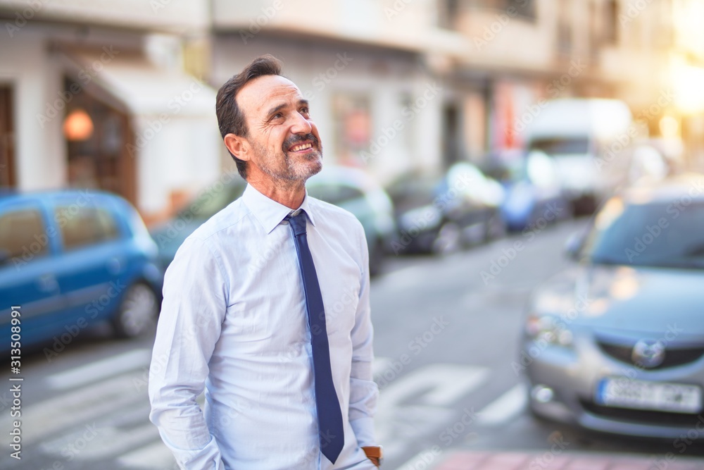 Middle age handsome businessman wearing shirt and tie standing on the street smiling
