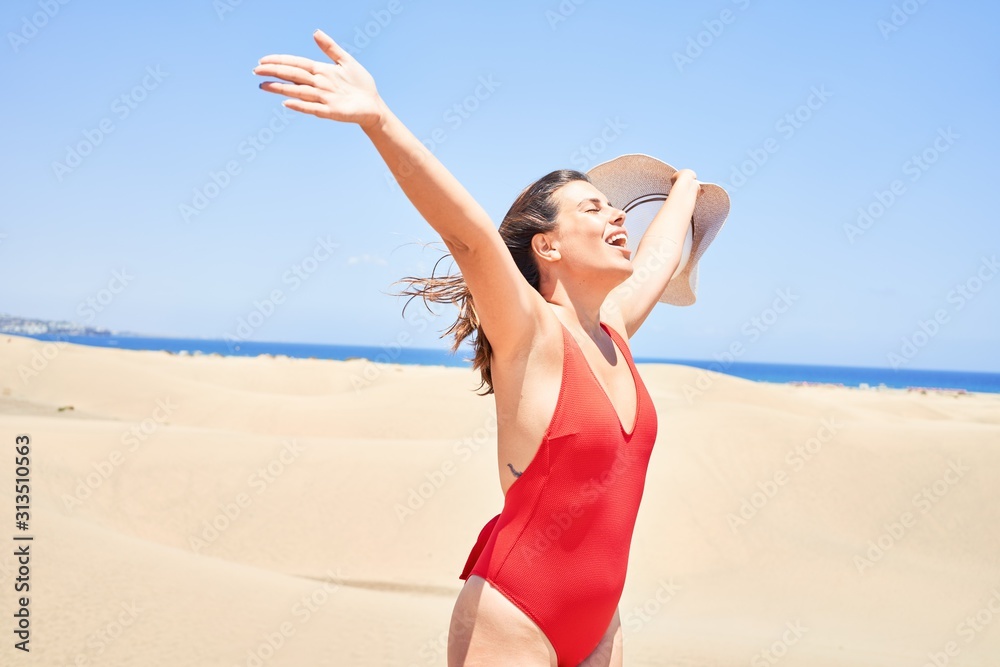 Young beautiful woman sunbathing with open arms wearing summer swinsuit at maspalomas dunes bech Young beautiful woman sunbathing with open arms wearing summer swinsuit at maspalomas dunes bech
