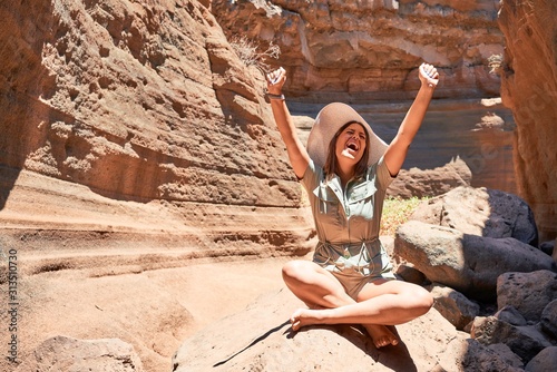 Young beauitufl hiker woman trekking natural orange mountain with arms raised celebrating summer holidays photo