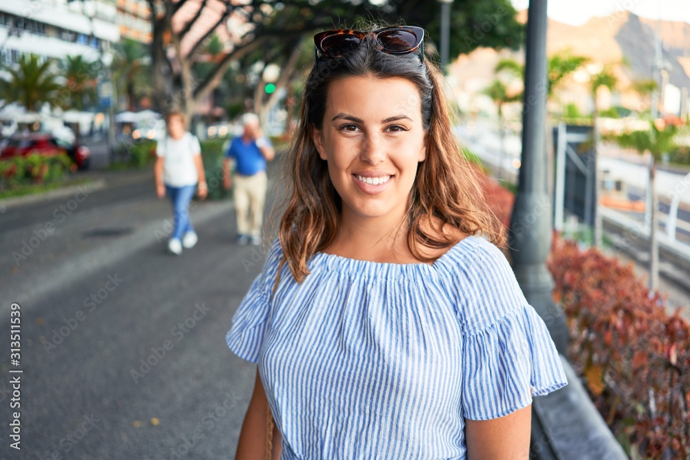 Young beautiful woman smiling happy walking on city streets on a sunny day of summer