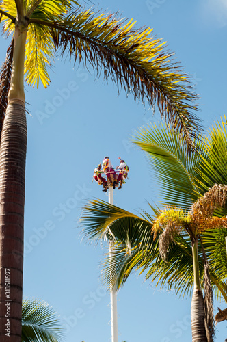 Mexican performance with men dropping upside down from pole on the beach