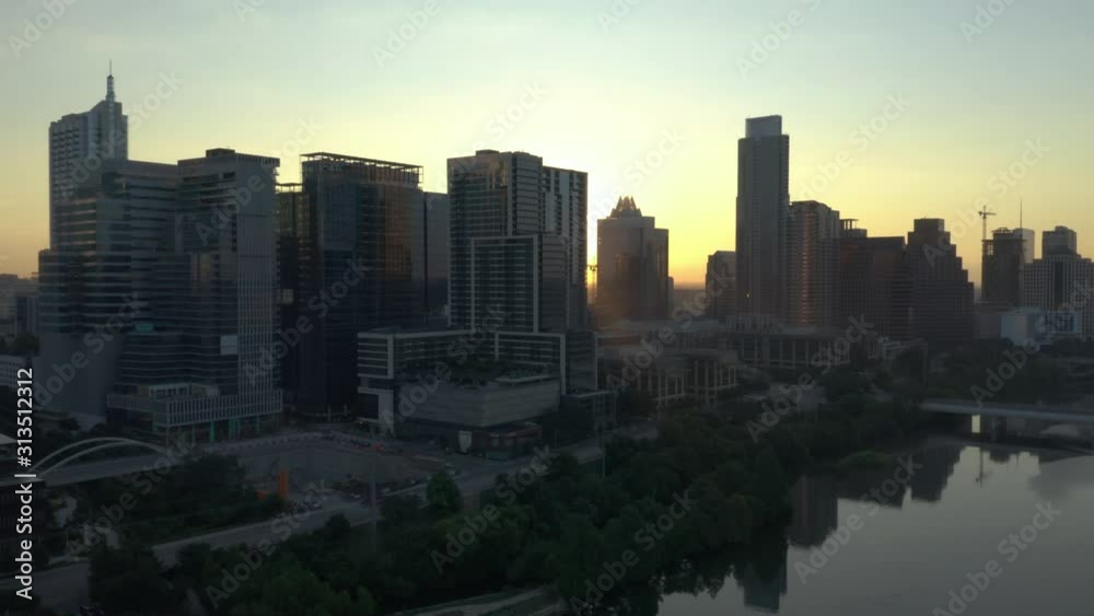 Cinematic Aerial video of the Austin Texas Skyline at with the sunrise with sunlight shining through the skyscrapers