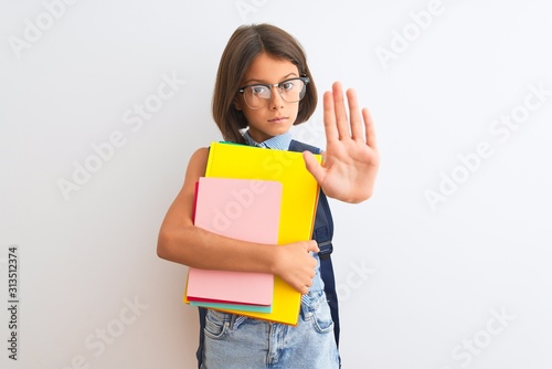 Beautiful student child girl wearing backpack glasses books over isolated white background with open hand doing stop sign with serious and confident expression, defense gesture