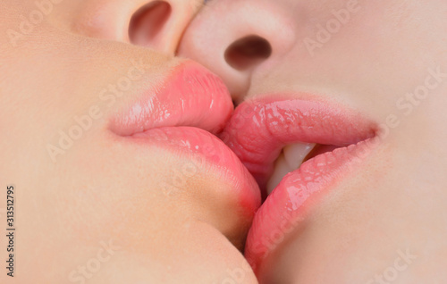 Kissing close up. Sexy plump lips without makeup. Two beautiful sexy lesbians in love. Passion and sensual kiss. Homosexual couple close up.