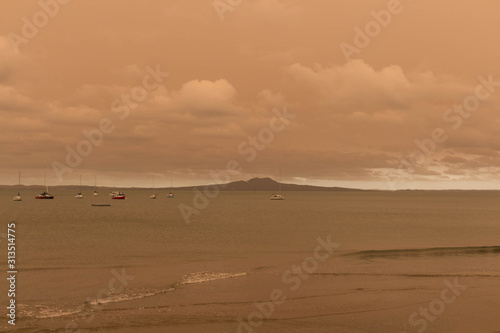 A haze from Australia s bushfires hangs over Torbay Beach  North Shore district of Auckland  New Zealand.