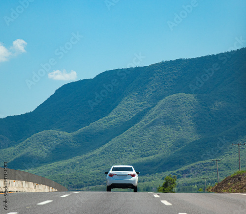 auto en carretera con paisaje de cerros y montañas 