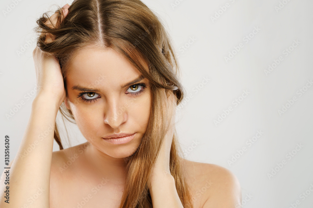 Beauty portrait of beautiful caucasian girl young brunette woman with natural perfect skin and makeup holding hands in hair looking to the camera at studio in front of white background Beauty portrait of beautiful caucasian girl young brunette woman with natural perfect skin and makeup holding hands in hair looking to the camera at studio in front of white background