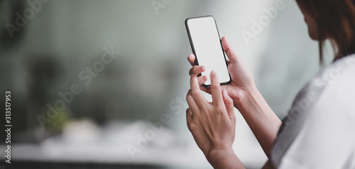 Close-up view of professional doctor using blank screen smartphone in her office room