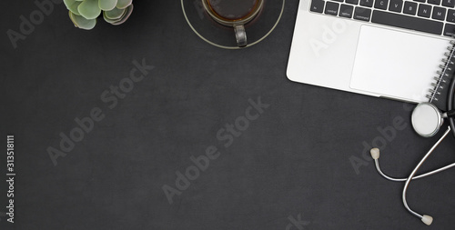 Overhead shot of dark trendy workplace with laptop computer and office supplies on black table