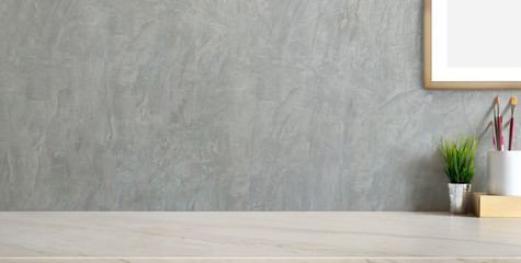 Cropped shot of trendy workplace with copy space and office supplies on marble background and loft grey wall