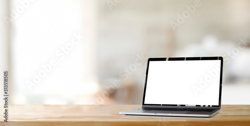 Cropped shot of open blank screen laptop computer on wooden table and copy space with blurred office