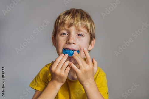 Six-year old boy shows myofunctional trainer. Helps equalize the growing teeth and correct bite, develop mouth breathing habit. Corrects the position of the tongue photo