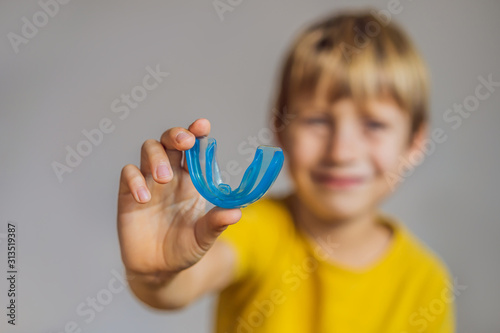 Six-year old boy shows myofunctional trainer. Helps equalize the growing teeth and correct bite, develop mouth breathing habit. Corrects the position of the tongue photo