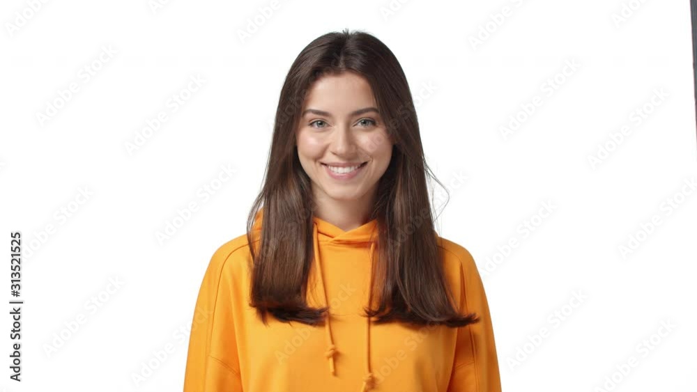Beauty, romance and women concept. Slow-motion adorable brunette girl in orange hoodie, glancing camera flirty and coquettish, making seductive gazes, smiling cute, blow air kiss, white background Beauty, romance and women concept. Slow-motion adorable brunette girl in orange hoodie, glancing camera flirty and coquettish, making seductive gazes, smiling cute, blow air kiss, white background