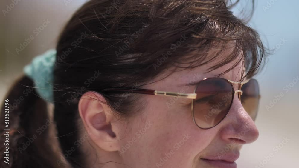 portrait of a happy woman in sunglasses turns head and looks at the camera, close up portrait of a happy woman in sunglasses turns head and looks at the camera, close up