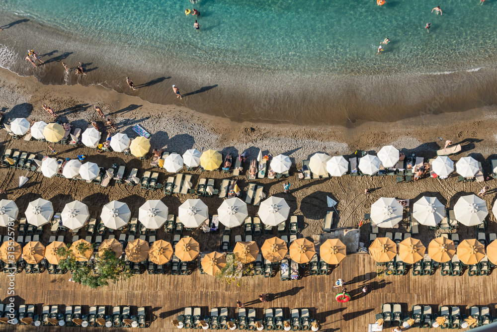 Turkish beach filled with holidaymakers, rows of sun loungers and parasols