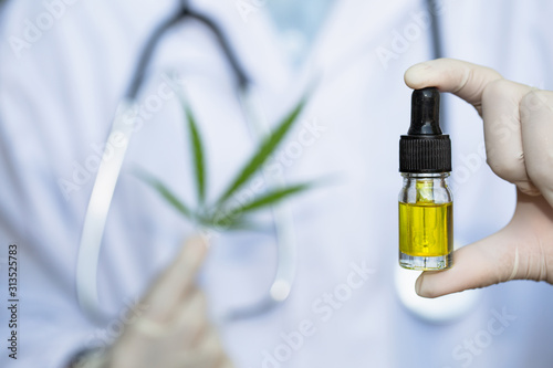 Glass bottle handle, CBD hemp oil. Doctors or researchers hold a bottle of hemp oil. Background with medical stethoscope.medical marijuana concept, CBD cannabis OIL. hemp product, close up
