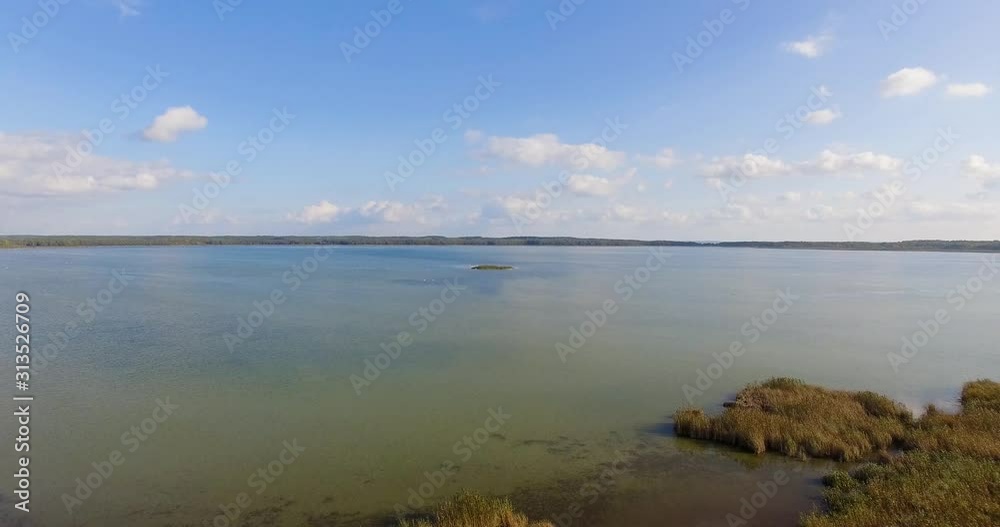 Flying over the beautiful landscape and Luknajno Lake in Poland on a bright sunny day - Aerial shot Flying over the beautiful landscape and Luknajno Lake in Poland on a bright sunny day - Aerial shot