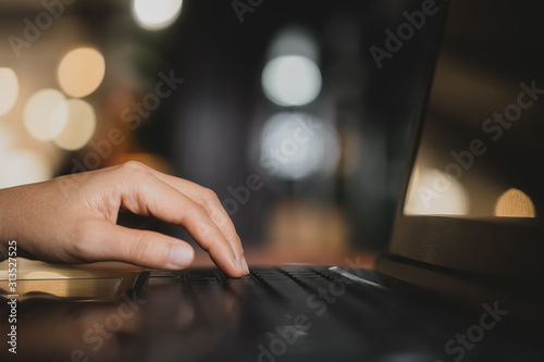 Woman hand using keyboard laptop on wood table in coffee shop.