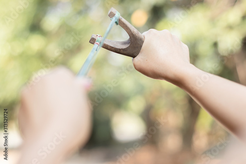 Human pulling slingshot and ready to fire.