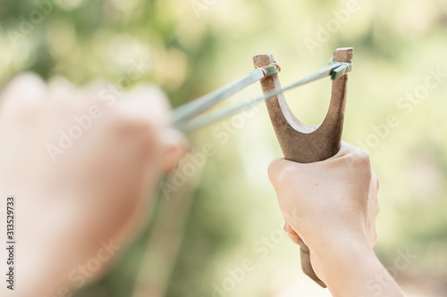 Human pulling slingshot and ready to fire.