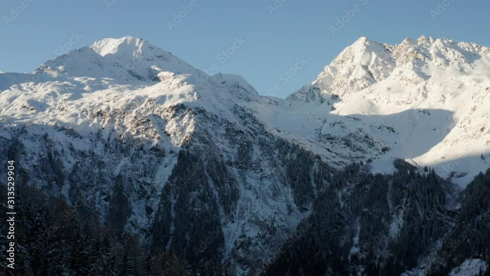 Drone shot showing the snow covered mountains on the other side of the valley during the last available sun light. Drone shot showing the snow covered mountains on the other side of the valley during the last available sun light.