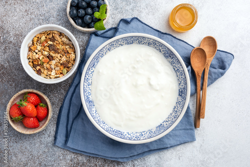 Breakfast Table with empty plate, yogurt, granola and berries. Top view with copy space for text