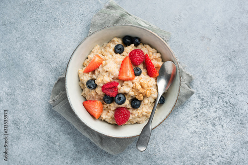 Oatmeal porridge with summer berries on concrete backdrop. Top view. Healthy food, fitness weight loss concept