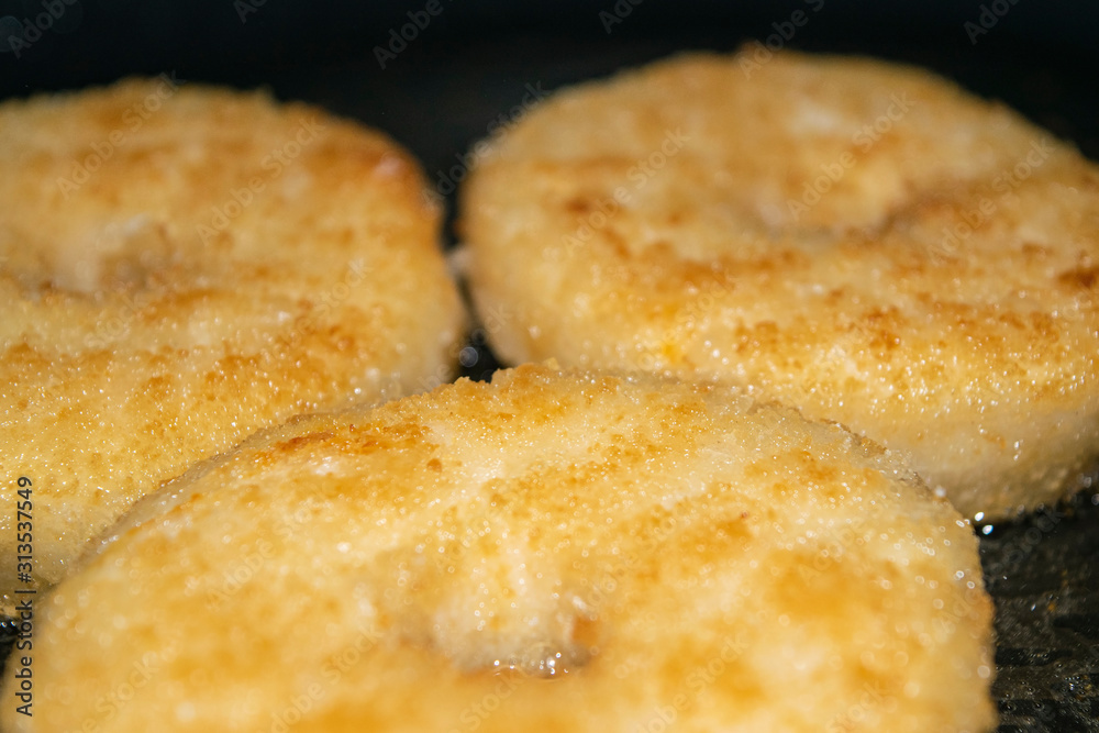 Three minced chicken cutlets are fried in a pan in vegetable oil. Close up.