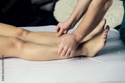 Lymphatic drainage massage of the hips. A male massage therapist gives a massage to a young woman 