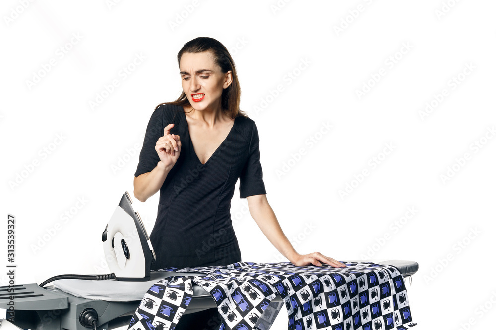 Housewife fatal woman in a black dress ironing things, blowing on a burnt finger. Isolated on a white background. Housewife fatal woman in a black dress ironing things, blowing on a burnt finger. Isolated on a white background.
