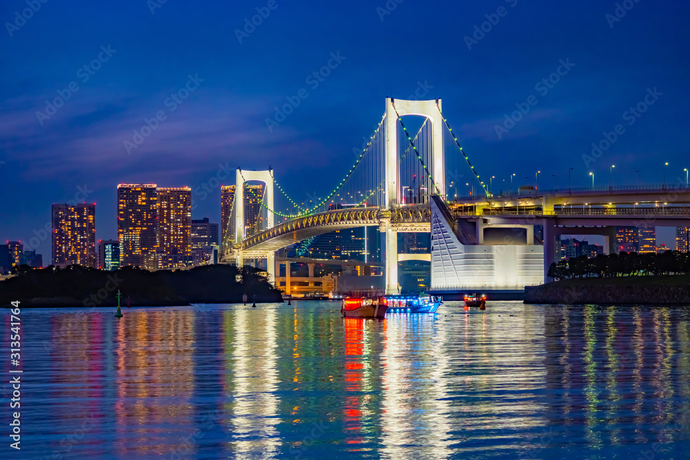 Japan. The Island Of Odaiba. Rainbow bridge in the evening. Travel to the artificial Islands of Japan. A trip to the island of Odaiba. Pacific Bay. Suspension bridge on the background of buildings.